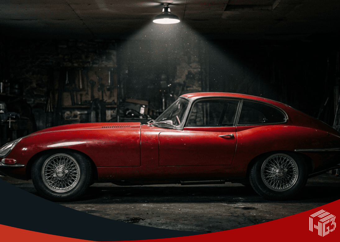 Classic red Jaguar E-Type in a garage under a single spotlight — design intent and automotive beauty